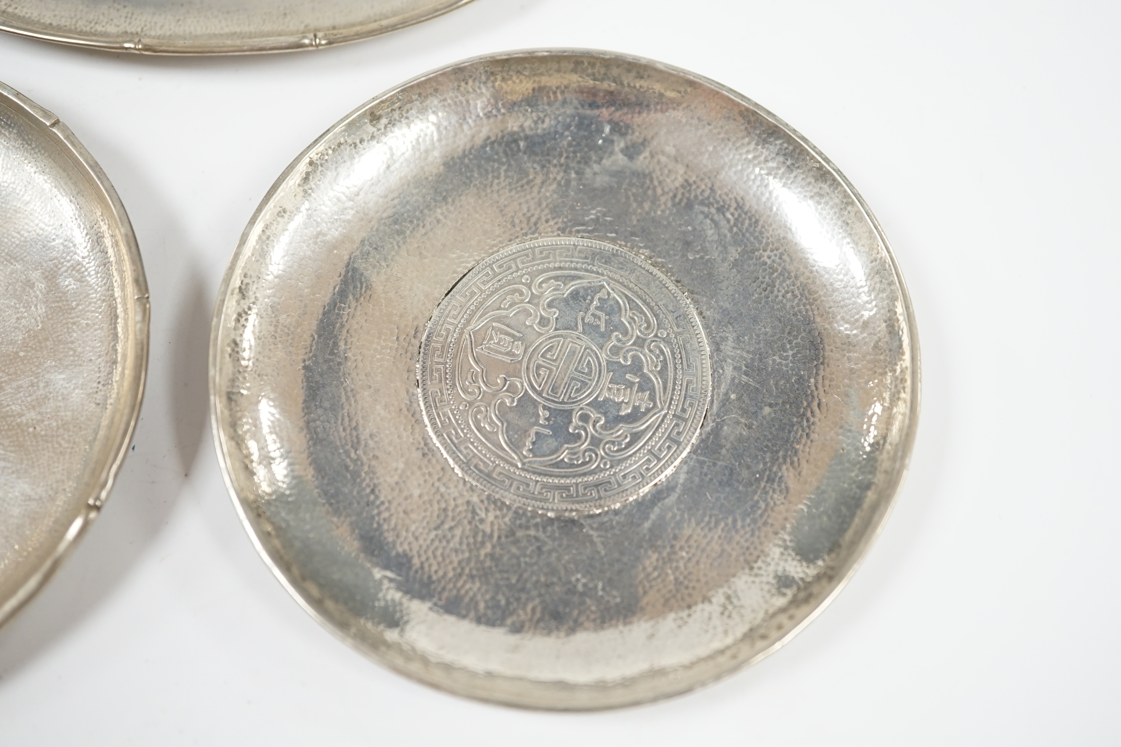Three assorted small Chinese white metal dish, each inset with a coin, largest 11.8cm. Condition - fair